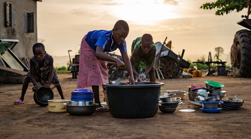 Niños en Nigeria lavan la vajilla en un pequeño contenedor de agua